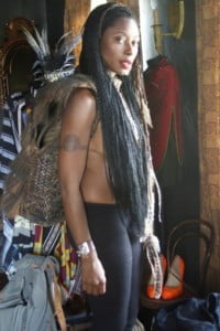 standing dark woman wearing many small long black braids
